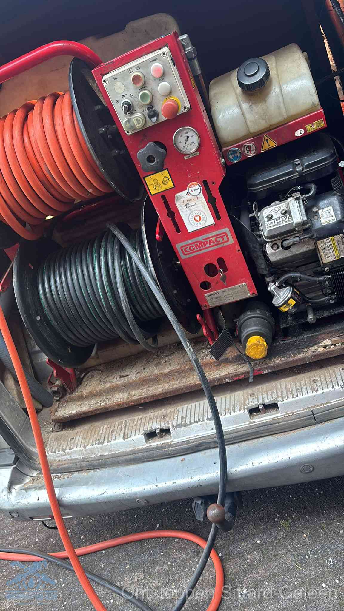 Een rood hogedruk-rioolreinigingstoestel met slangen in de laadbak van de bedrijfsbus, apparatuur voor een hardnekkige wc-verstopping in Sittard-Geleen