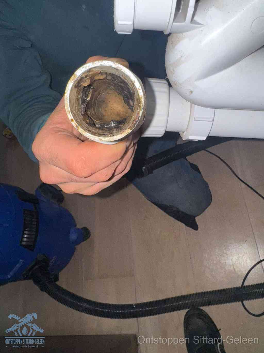 Een losgekoppelde afvoerbuis die van binnen volledig is dichtgeslibd met vet en aanslag, de meest voorkomende oorzaak van een verstopte gootsteen in Sittard-Geleen