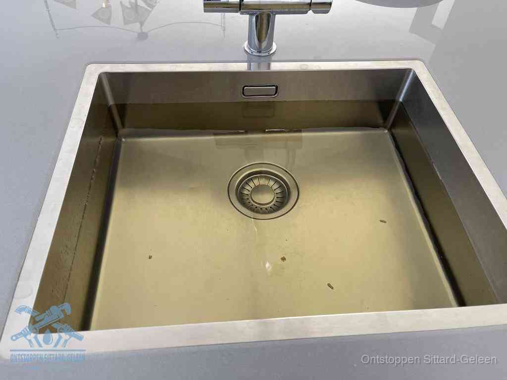 Stilstaand water in een rvs spoelbak dat niet wegloopt, een duidelijk signaal van een gootsteenverstopping in Sittard-Geleen