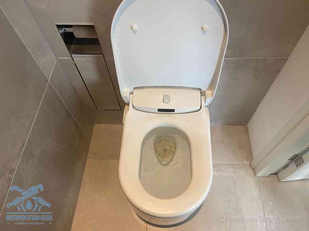 Een wit hangtoilet waarin een prop wc-papier op het water blijft drijven, een duidelijk signaal van een verstopte wc in Sittard-Geleen