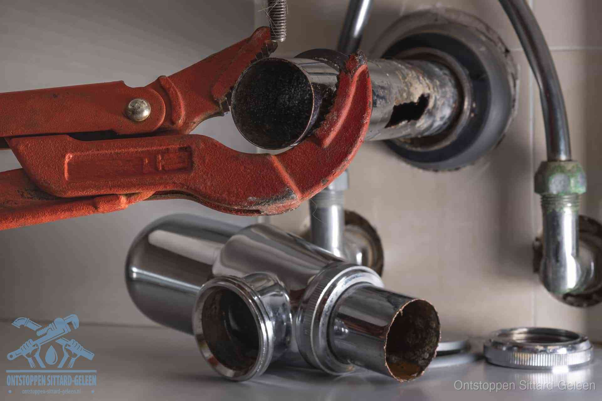 Een sterk vervuilde en verkalkte sifon die met een waterpomptang wordt gedemonteerd, vaak de bron van stank uit de gootsteen in Sittard-Geleen