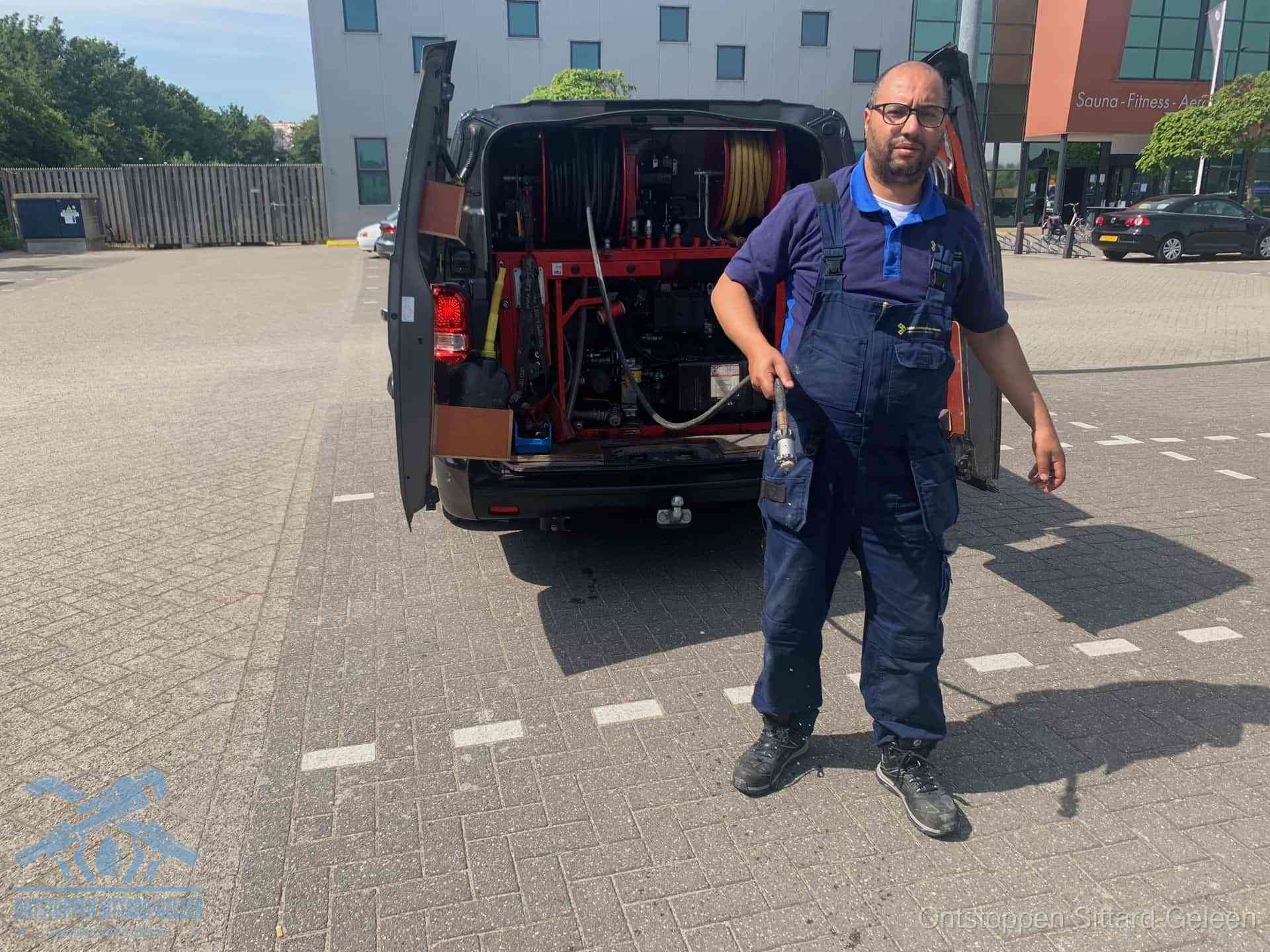 Een monteur bij zijn bestelbus met een hogedruk- en rioolreinigingsunit, klaar om de oorzaak van terugkerende wc-verstoppingen aan te pakken in Sittard-Geleen