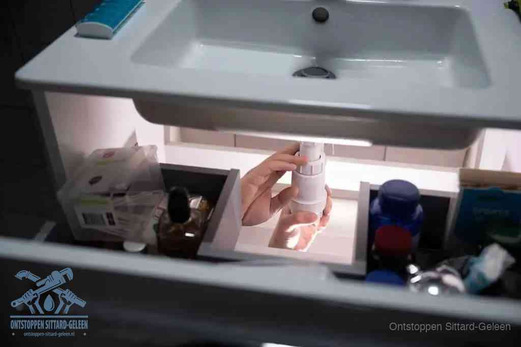 Een pompfles met zeep boven een wastafel in de toiletruimte, de warm water en afwasmiddel-methode om de wc te ontstoppen in Sittard-Geleen
