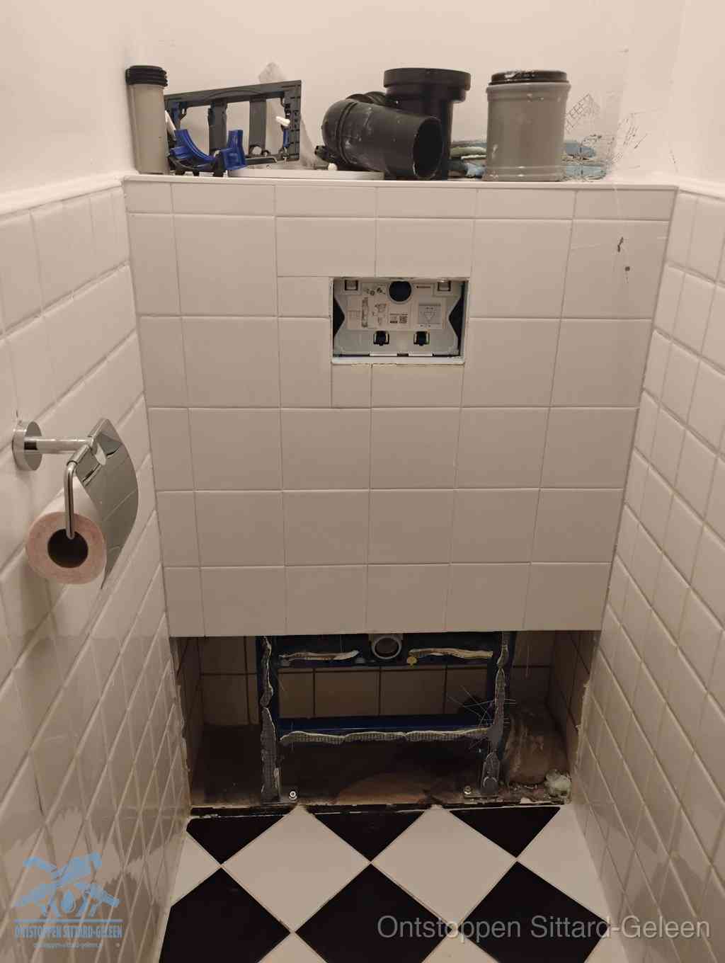 Een toiletruimte waar het hangtoilet en de inbouwreservoir-onderdelen zijn vrijgelegd voor onderhoud, periodiek nazicht voorkomt een wc-verstopping in Sittard-Geleen