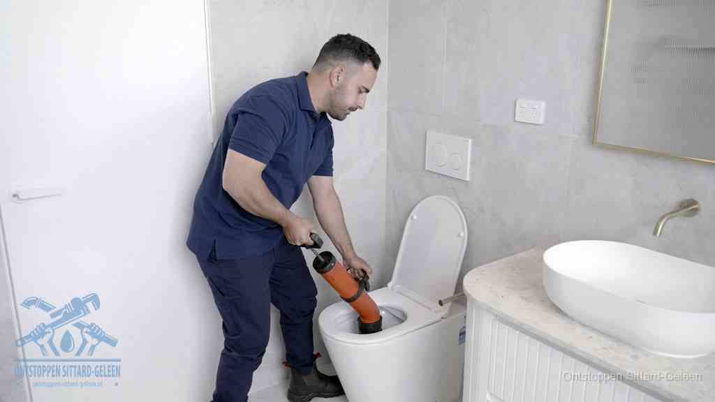 Een monteur gebruikt een handmatige perspomp (toiletontstopper) op een wandcloset tijdens het professioneel wc ontstoppen in Sittard-Geleen